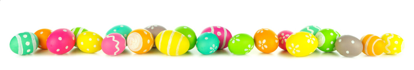 Easter eggs scattered forming a long border isolated on a white background. Vibrant colors.