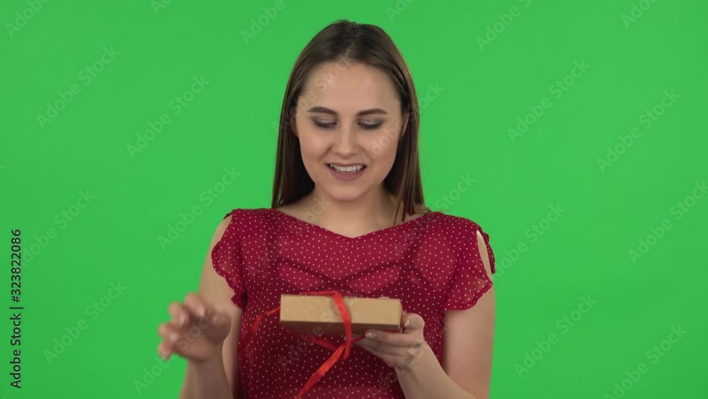Portrait of tender girl in red dress is opening the gift, very surprised and rejoicing. Green screen Portrait of tender girl in red dress is opening the gift, very surprised and rejoicing. Green screen