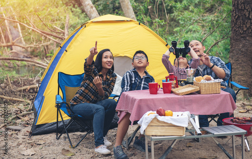 Happy Family Asian Enjoying picnic and Camping Holiday In Countryside
