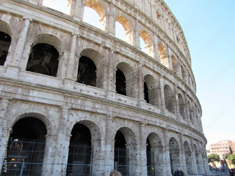 Exterior view of the Colosseum, also known as the Flavian Amphitheater, located in Rome, Italy with blue sky in the background 