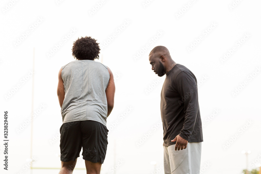 American Football coach training a young athlete. American Football coach training a young athlete.
