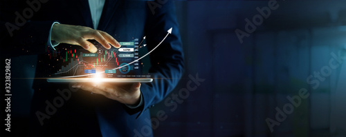 Businessman holding tablet and analysis stock market, currency exchange and banking, showing a growing virtual hologram of statistics, graph and chart, Business growth, planing and strategy  concept. photo