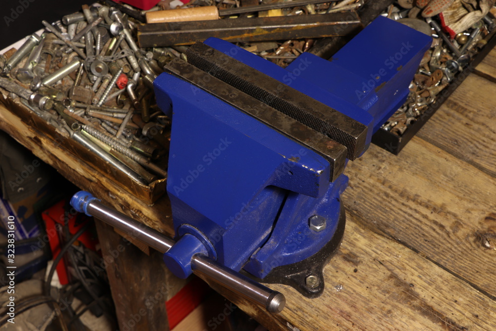 Fototapeta premium Blue vise on a wooden table. Bench tools. Vice.