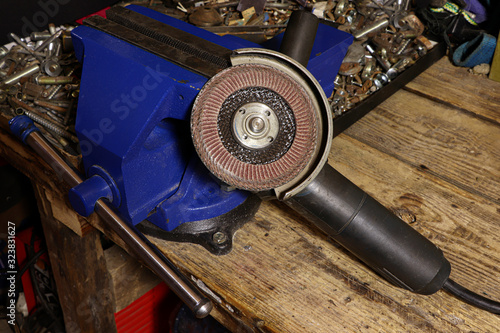 Angular grinding machine. Blue vise on a wooden table. Bench tools. Vice.