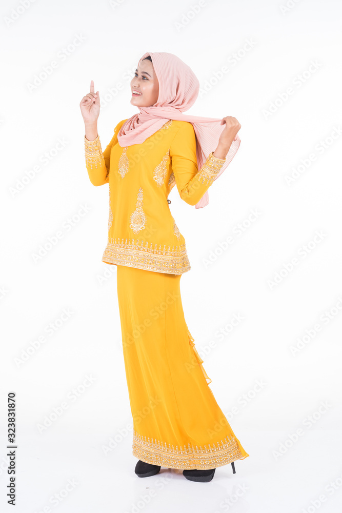 Obraz premium Beautiful female Muslim model in modern kurung and hijab, a modern lifestyle apparel for Muslim women isolated on white background. Beauty and hijab fashion concept. Full length portrait
