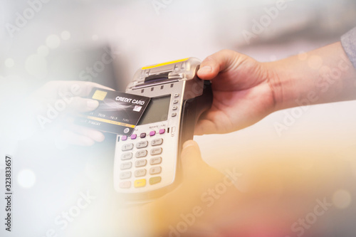 Retail, credit card payment service. Customer paying for order Product. Woman paying with card contactless in the shop store. Close-up view on the terminale and card photo