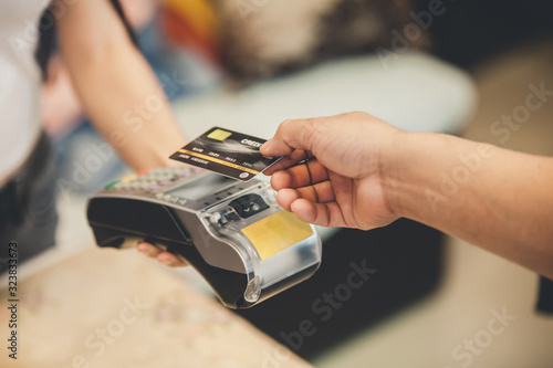 Retail, credit card payment service. Customer paying for order Product. Woman paying with card contactless in the shop store. Close-up view on the terminale and card photo
