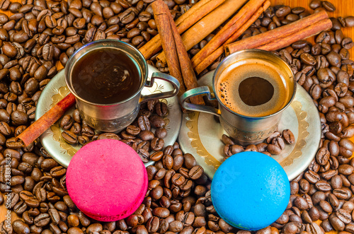 Two metal coffee cups with coffee beans and macaroni cookies. photo