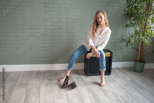 Wallpaper Mural Young beautiful woman sitting on subwoofer with bare feet next to green plant Torontodigital.ca
