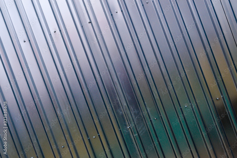 Silver tin iron wall with vertical and diagonal stripes from a metal profile of a metal sheet. Texture, background