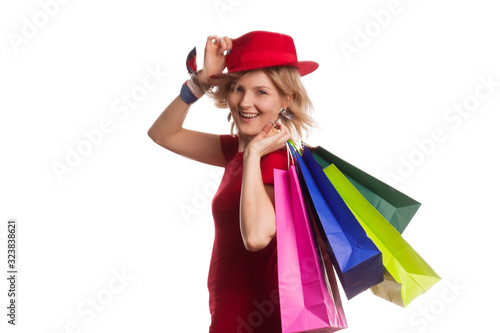 blonde girl with short hair on isolat in a red dress and a red hat, with colored paper shopping bags. The concept of shopping or sales,
