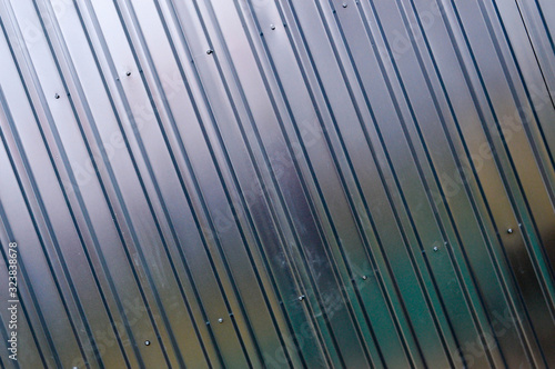 Silver tin iron wall with vertical and diagonal stripes from a metal profile of a metal sheet. Texture, background