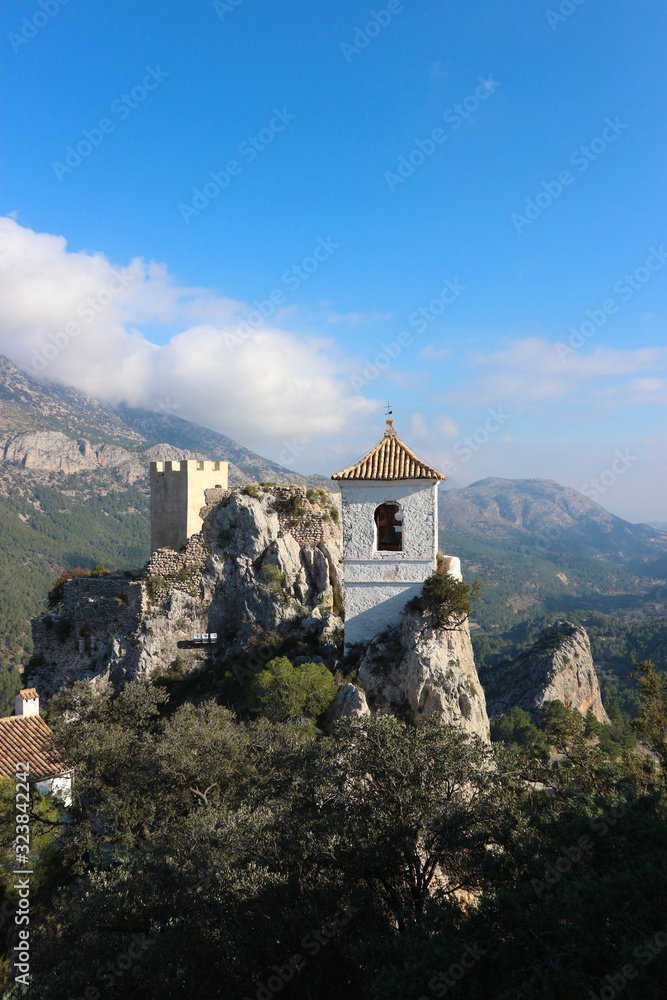 View to castle watch tower and bell tower in Castell de guadalest with mountains on the background, Spain