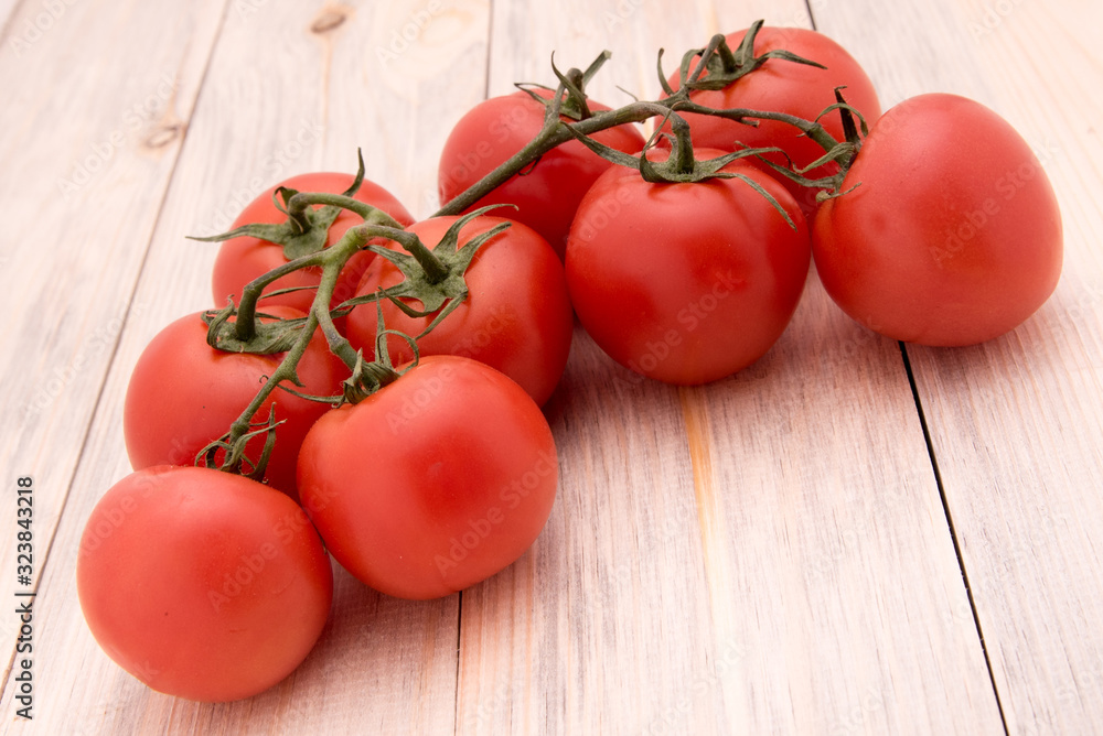 Juicy red tomatoes on a twig on a wooden background Juicy red tomatoes on a twig on a wooden background