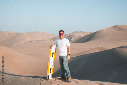 Man enjoying sand boarding at Huachina desert sand dunes Peru South America photo