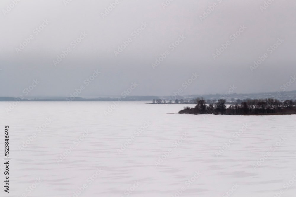 Landscape view of a large frozen river on a gray cloudy day.