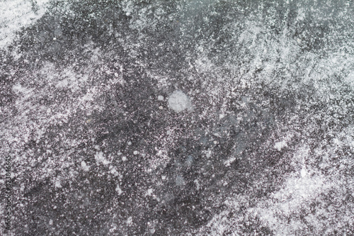 Texutured ise surface of frozen lake. Close up. Scattered white snow around. Winter background.