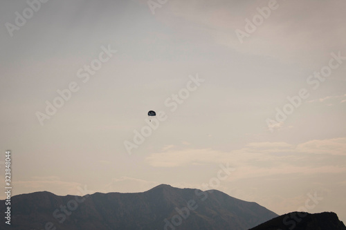 Skydiver flying far in the sky over the mountains.