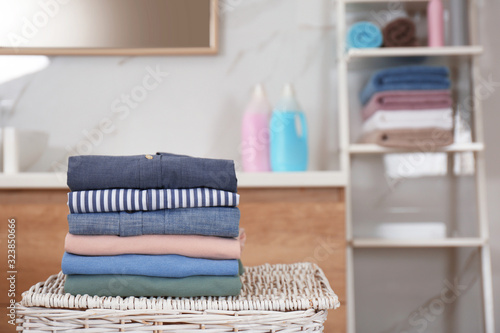 Stack of fresh laundry on basket in bathroom. Space for text