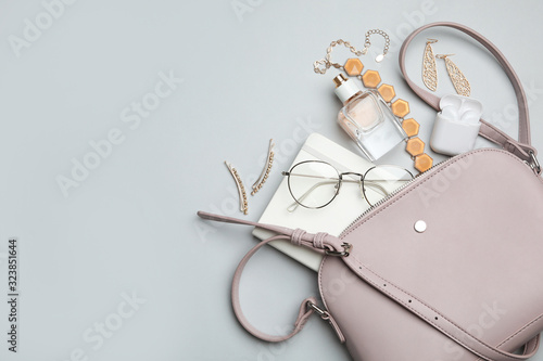 Stylish woman's bag with accessories on light grey background, flat lay. Space for text photo