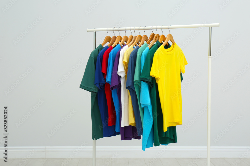 Rack with stylish colorful t-shirts in room