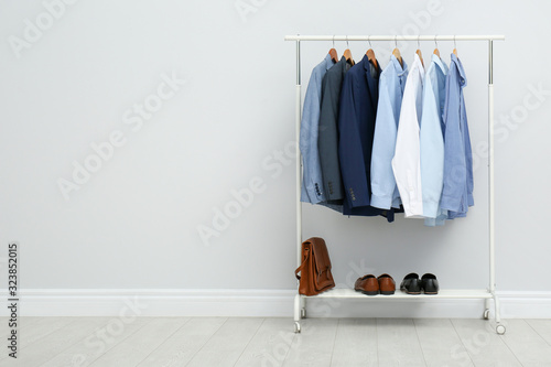 Rack with stylish men's clothes in room. Space for text