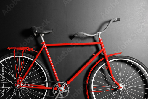 Fototapeta Naklejka Na Ścianę i Meble -  Red bicycle hanging on black wall, closeup