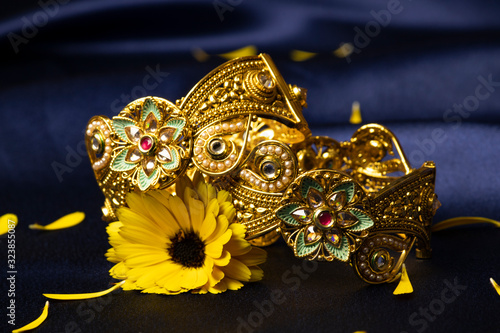 Jaipuri wide gold plated bangles on silk blue background with yellow flower