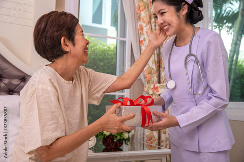  Asian young nurse giving a gift box to elderly woman for Birthday, mother's day, Christmas and New year