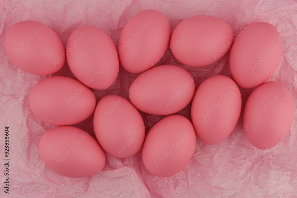 Lots of pink painted Easter eggs on crumpled pink wrapping paper. Close-up. Flat lay, top view