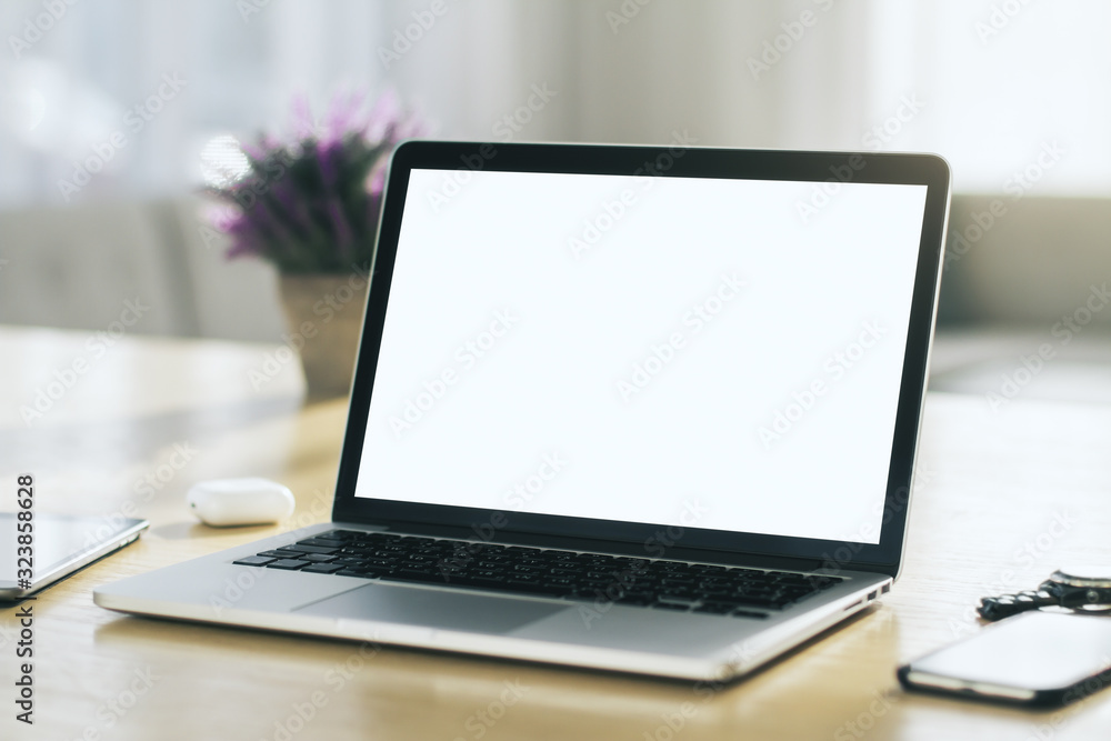 Close up of modern laptop with blank screen on wooden table in sunny interior, mockup. Business and technology concept Close up of modern laptop with blank screen on wooden table in sunny interior, mockup. Business and technology concept