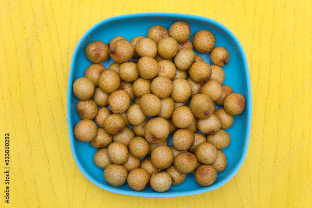 longan fruit in blue bowl on yellow table longan fruit in blue bowl on yellow table