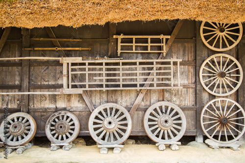 Photograph of several wooden wheels resting on a wooden wall