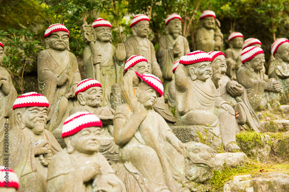 Photograph of Buddha statues with red and white caps