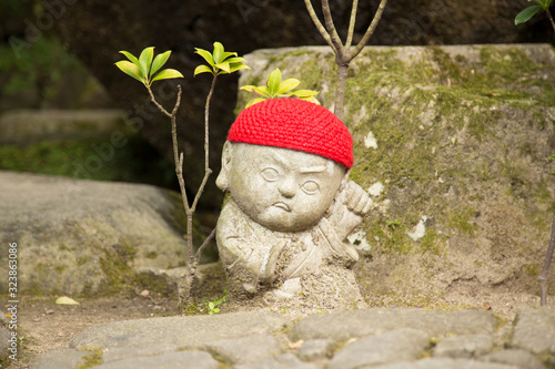 Photograph of a statue of a small angry Buddha with a red cap