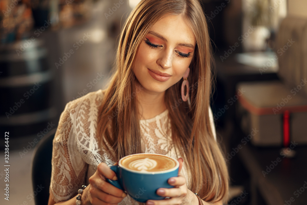 Beautiful young woman sitting in coffee shop enjoying her drink Beautiful young woman sitting in coffee shop enjoying her drink