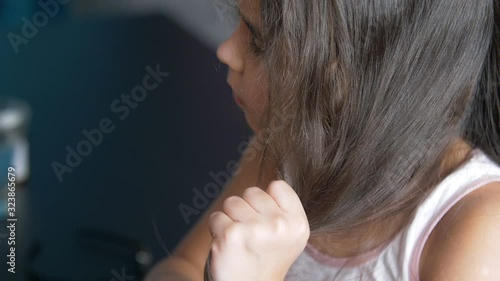 Little child girl with hair brush in the room. Girl brushing her hair. Long beautiful curly hair. Close up