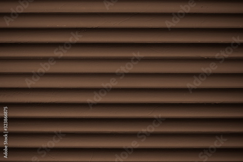 Metal striped pattern. Dark brown ribbed siding texture. Lines of fence, abstract grooved background.