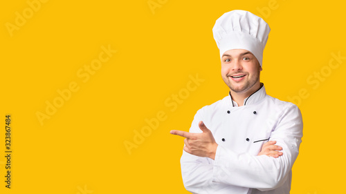 Male Chef Pointing Fingers Aside Standing On Yellow Background, Panorama