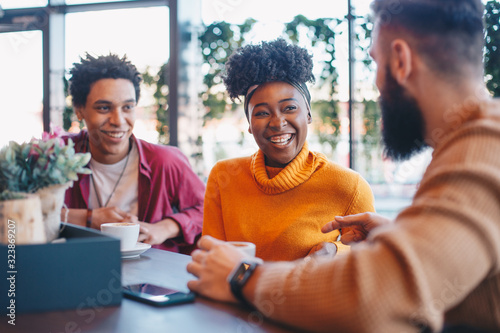 Foto Two guys and a girl sitting in a cafe, talking