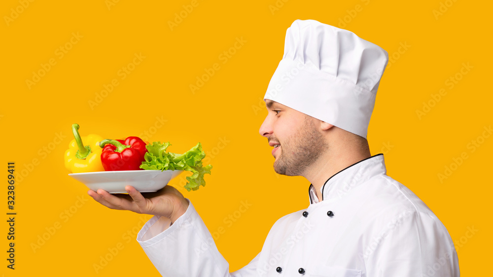 Cook Man Holding Plate With Vegetables In Studio, Side-View, Panorama Cook Man Holding Plate With Vegetables In Studio, Side-View, Panorama