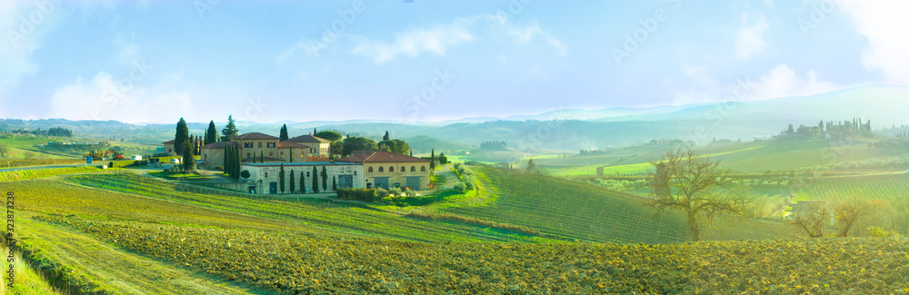 Landscape of Tuscany beautifully illuminated by the sun immersed in the green and blue sky.
