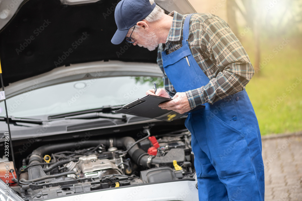 Car mechanic checking a car engine Car mechanic checking a car engine