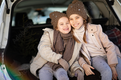 Two sisters sitting in the trunk of a car and hug