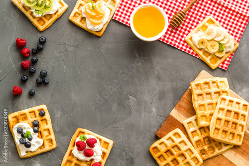 Breakfast with freashly baked belgian waffles on grey background top-down frame copy space