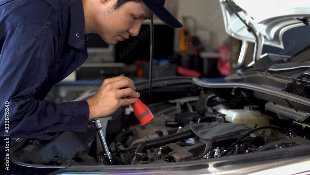 male mechanic holding and shining flashlight to checking a car engine problem