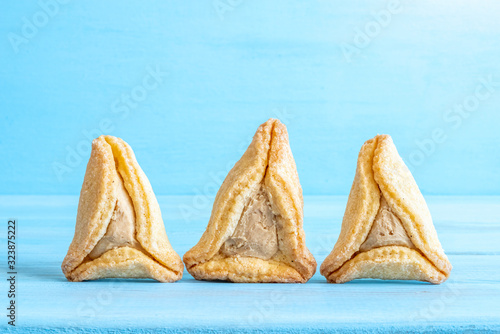 Hamantashen with halva stuffing on blue wooden background. Free space for text.