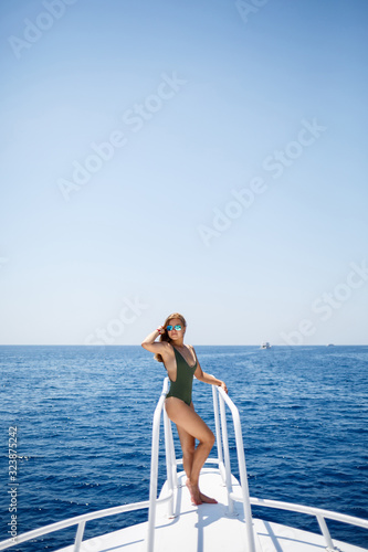A girl with a beautiful figure in a green swimwear. She is on a white yacht in the red sea