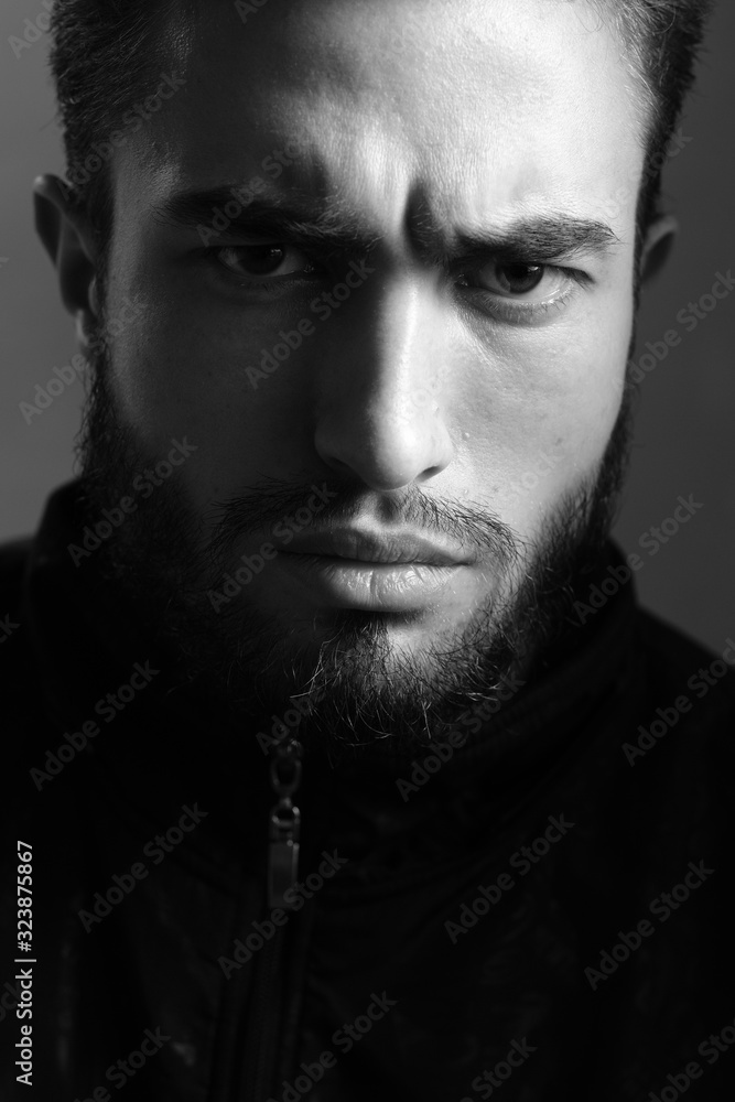 Fototapeta premium Close-up czarno-biały portret młodego przystojnego mężczyzny rasy kaukaskiej w studio. Mężczyzna przejawia różne ludzkie emocje.