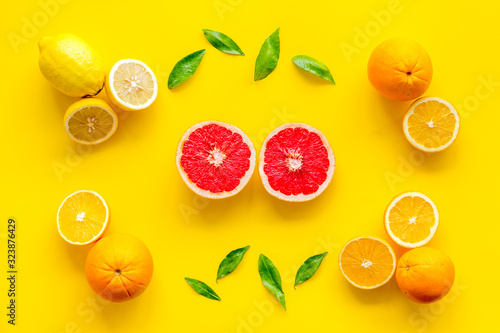 Citrus pattern. Cut lemon and grapefruits and leaves on yellow background top-down